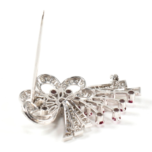 13 - An Art Deco white gold ruby and diamond white spray brooch pin. The brooch set with a central round ... 