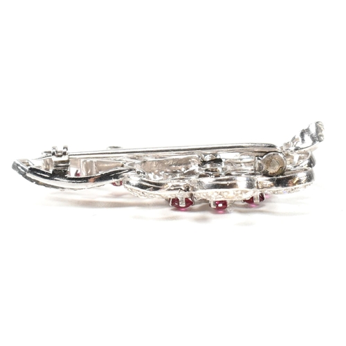 13 - An Art Deco white gold ruby and diamond white spray brooch pin. The brooch set with a central round ... 