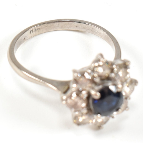 14 - An 18ct gold sapphire and diamond cluster ring. The ring set with a central round cut sapphire frame... 