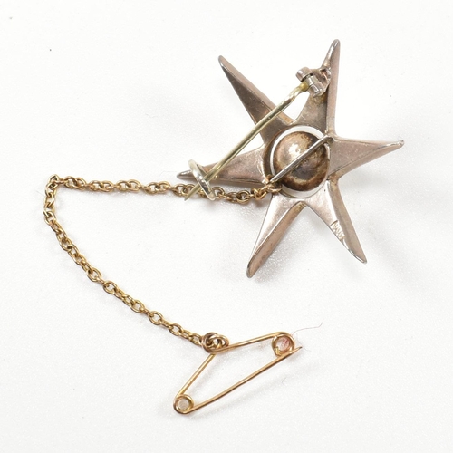 143 - An antique silver and paste star brooch pin. The brooch in the form of an eight pointed star set wit... 