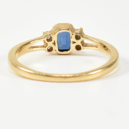 144 - An 18ct gold sapphire and diamond ring. The ring having a central bezel set emerald cut sapphire fla... 