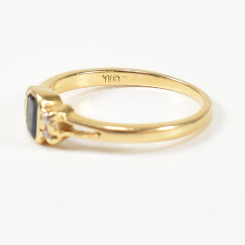 144 - An 18ct gold sapphire and diamond ring. The ring having a central bezel set emerald cut sapphire fla... 