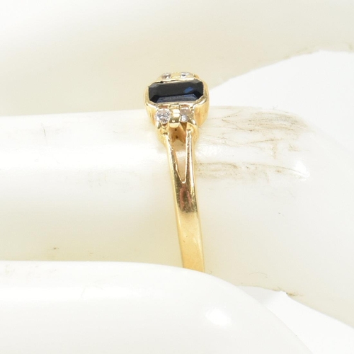 144 - An 18ct gold sapphire and diamond ring. The ring having a central bezel set emerald cut sapphire fla... 