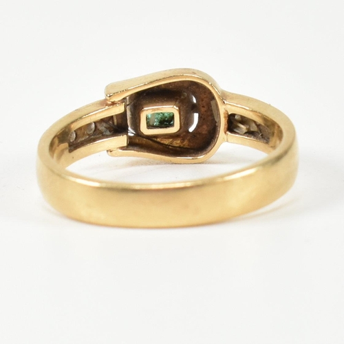 148 - An 18ct gold, diamond and emerald buckle ring. The gold buckle ring having a bezel set east-west eme... 