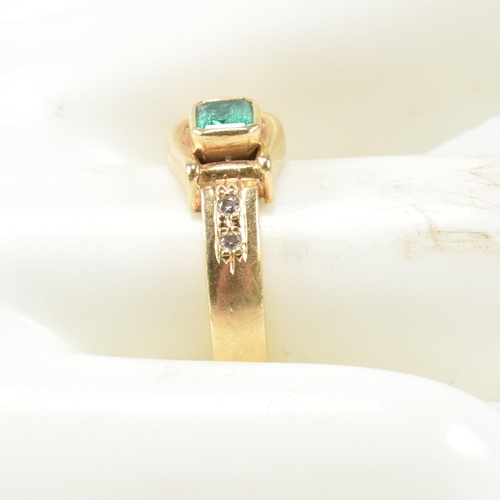 148 - An 18ct gold, diamond and emerald buckle ring. The gold buckle ring having a bezel set east-west eme... 