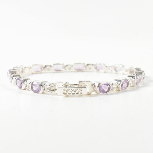 156 - A 925 silver, amethyst and CZ line bracelet. The bracelet set with half bezel set oval cut amethysts... 