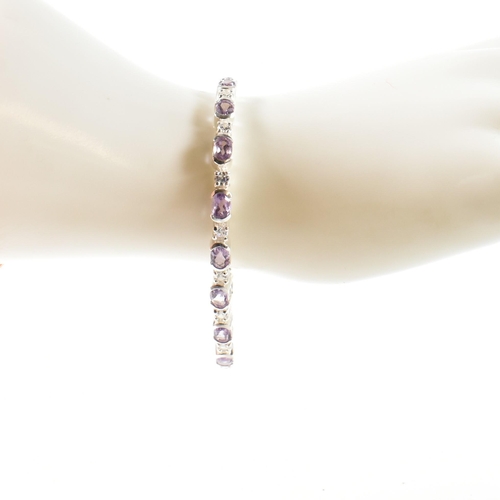 156 - A 925 silver, amethyst and CZ line bracelet. The bracelet set with half bezel set oval cut amethysts... 