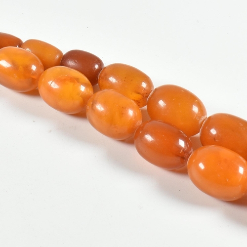 17 - An vintage amber bead necklace. The amber necklace having graduating oval beads strung with later cl... 