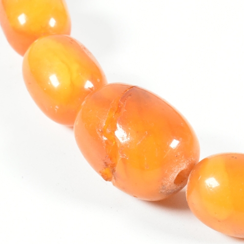 17 - An vintage amber bead necklace. The amber necklace having graduating oval beads strung with later cl... 