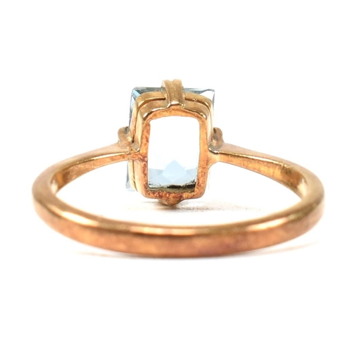 177 - A 22ct gold and blue stone ring. The ring set with a single double claw set baguette cut blue stone ... 