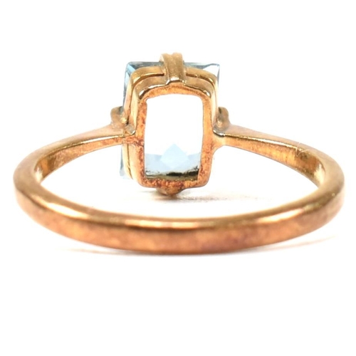 177 - A 22ct gold and blue stone ring. The ring set with a single double claw set baguette cut blue stone ... 