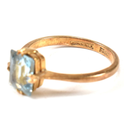 177 - A 22ct gold and blue stone ring. The ring set with a single double claw set baguette cut blue stone ... 