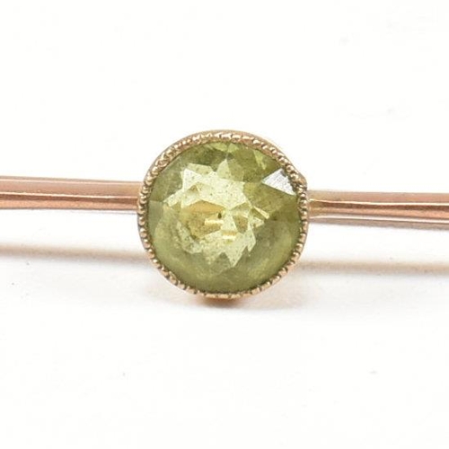 179 - A 9ct gold and peridot bar brooch pin. The 9ct gold brooch pin set with a central bezel set round cu... 