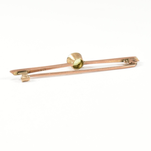 179 - A 9ct gold and peridot bar brooch pin. The 9ct gold brooch pin set with a central bezel set round cu... 