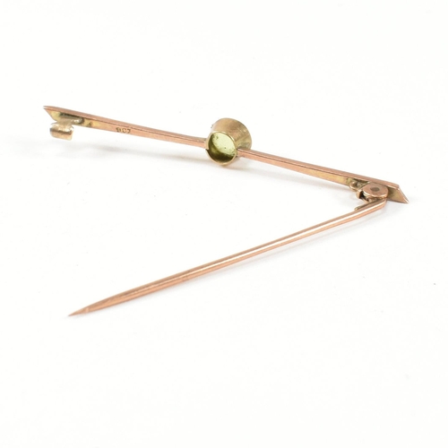 179 - A 9ct gold and peridot bar brooch pin. The 9ct gold brooch pin set with a central bezel set round cu... 