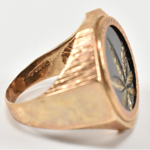 195 - A hallmarked 9ct gold signet ring having an onyx plaque with incised gilded cannabis leaf motif havi... 