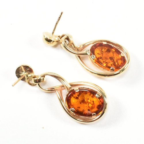 204 - A pair of hallmarked 14ct gold and amber pendant earrings. The pendant earrings having a bezel set o... 