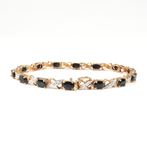 218 - A 9ct gold, sapphire and diamond line bracelet. The bracelet having fourteen oval cut sapphires inte... 