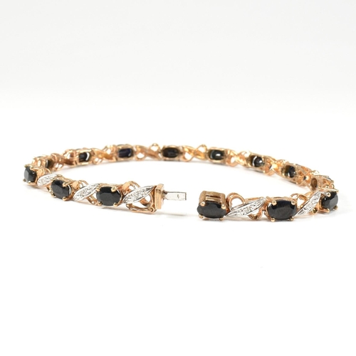 218 - A 9ct gold, sapphire and diamond line bracelet. The bracelet having fourteen oval cut sapphires inte... 