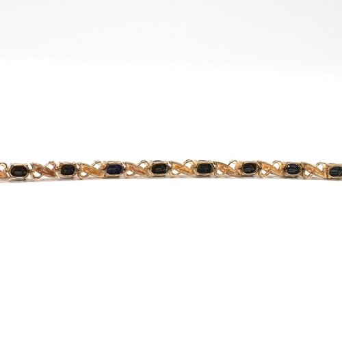 218 - A 9ct gold, sapphire and diamond line bracelet. The bracelet having fourteen oval cut sapphires inte... 