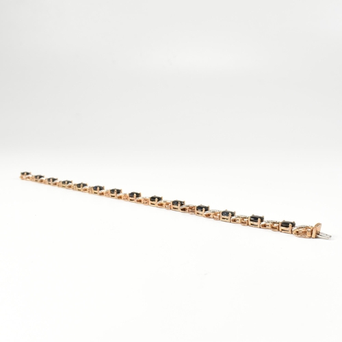 218 - A 9ct gold, sapphire and diamond line bracelet. The bracelet having fourteen oval cut sapphires inte... 