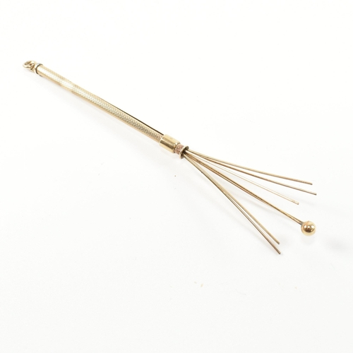 241 - A retro hallmarked 9ct gold champagne swizzle stick fob. The vintage cocktail stirrer having an engi... 