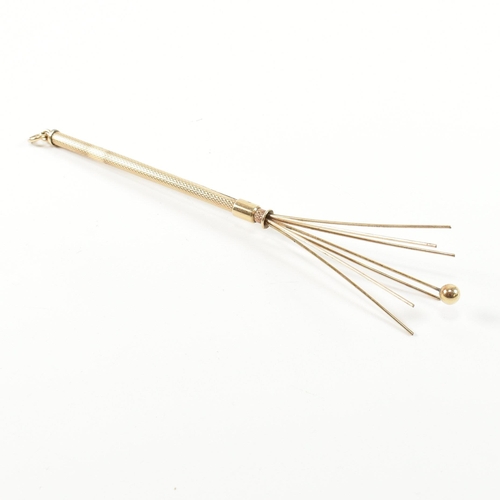 241 - A retro hallmarked 9ct gold champagne swizzle stick fob. The vintage cocktail stirrer having an engi... 