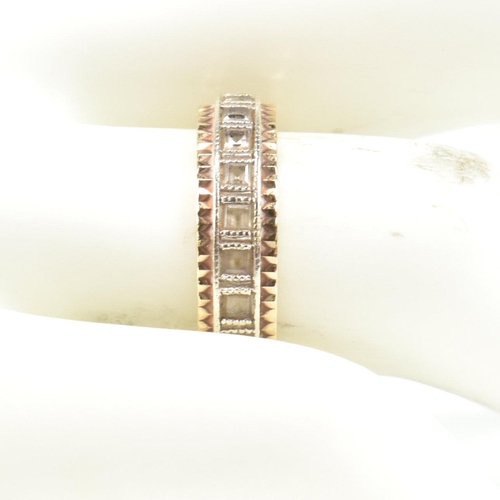 251 - A hallmarked 9ct gold and white stone eternity ring. The two tone metal ring set with a central row ... 