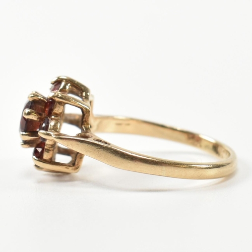 283 - A hallmarked 9ct gold and garnet cluster ring. The cluster ring having a central round cut garnet su... 