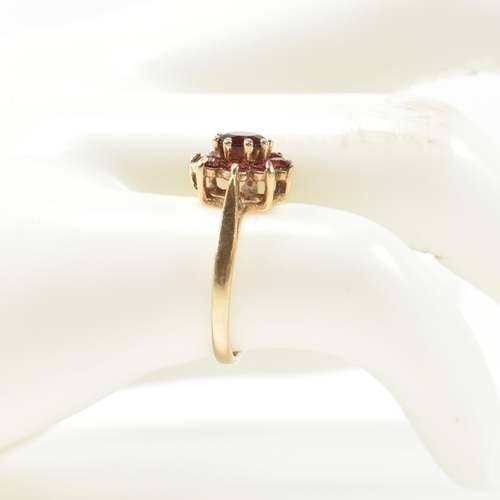 283 - A hallmarked 9ct gold and garnet cluster ring. The cluster ring having a central round cut garnet su... 