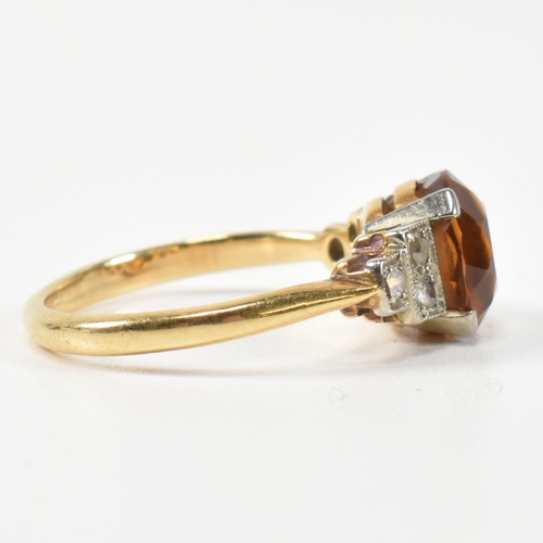 313 - An 18ct gold and citrine ring. The ring having a central round cut citrine to shoulders each set wit... 