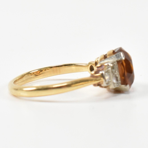 313 - An 18ct gold and citrine ring. The ring having a central round cut citrine to shoulders each set wit... 