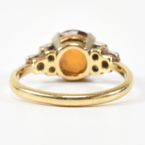 313 - An 18ct gold and citrine ring. The ring having a central round cut citrine to shoulders each set wit... 