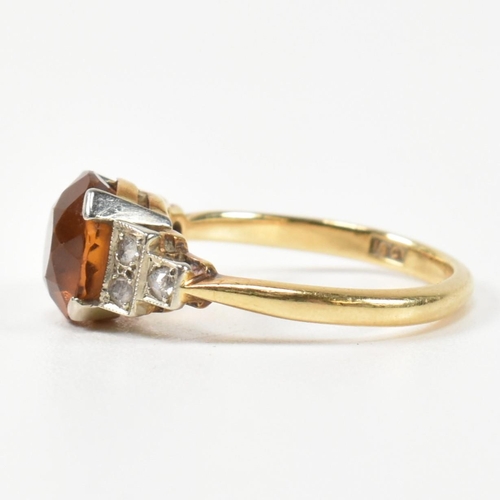 313 - An 18ct gold and citrine ring. The ring having a central round cut citrine to shoulders each set wit... 