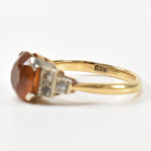 313 - An 18ct gold and citrine ring. The ring having a central round cut citrine to shoulders each set wit... 