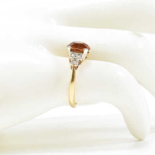 313 - An 18ct gold and citrine ring. The ring having a central round cut citrine to shoulders each set wit... 