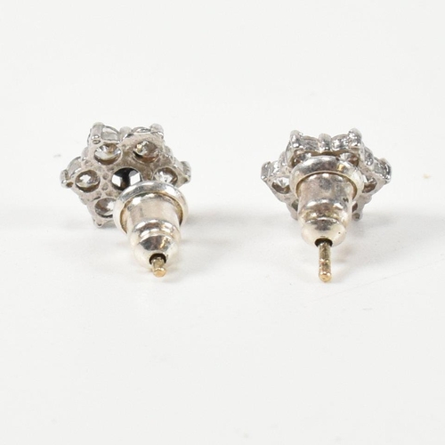 322 - A pair of hallmarked 9ct gold, CZ and sapphire cluster earrings. The stud earrings set with a centra... 