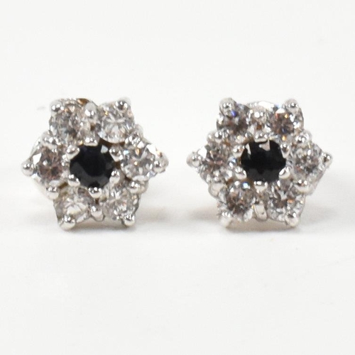 322 - A pair of hallmarked 9ct gold, CZ and sapphire cluster earrings. The stud earrings set with a centra... 