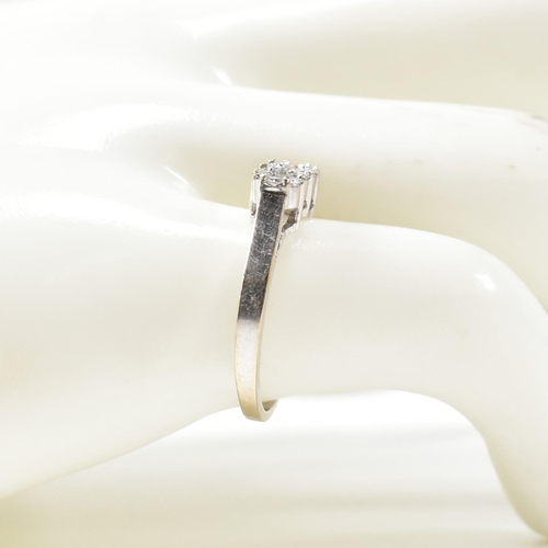 329 - An 18ct white gold and diamond ring. The ring set with three round cut diamonds surrounded by eighte... 