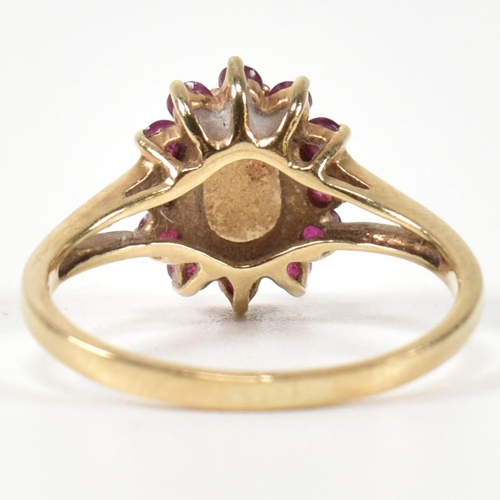 347 - A hallmarked 9ct gold, opal and ruby cluster ring. The ring having a central opal cabochon surrounde... 