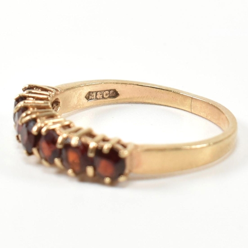 353 - A hallmarked 9ct gold and garnet seven stone half hoop ring. The 9ct gold ring having a row of seven... 