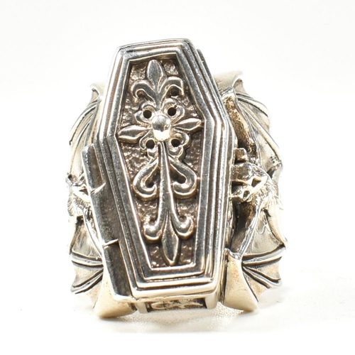 357 - A silver coffin locket ring. The ring in form of a coffin having hinged compartment that opens to re... 