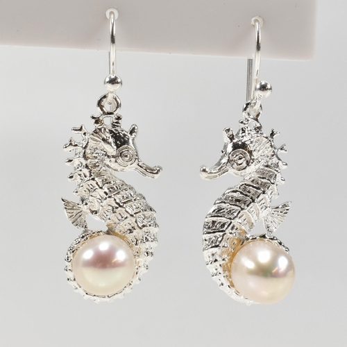 362 - A pair of silver and pearl set earrings in the form of sea horses. Unmarked. Measures 2.5cm. All wei... 