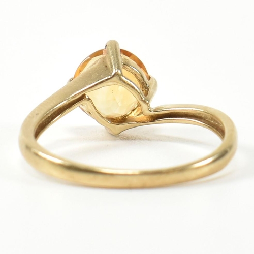 366 - A hallmarked 9ct gold and citrine cross over ring. The ring having a compass four claw set round cut... 