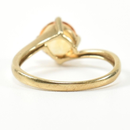 366 - A hallmarked 9ct gold and citrine cross over ring. The ring having a compass four claw set round cut... 