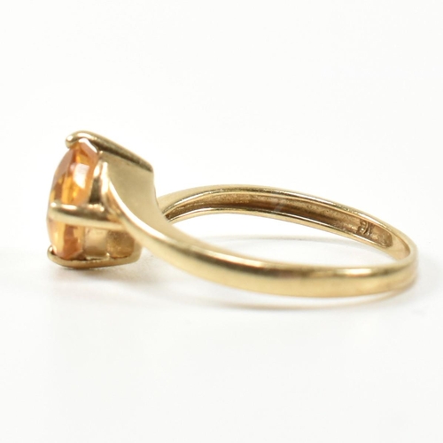 366 - A hallmarked 9ct gold and citrine cross over ring. The ring having a compass four claw set round cut... 