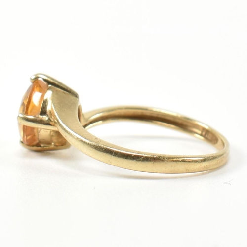 366 - A hallmarked 9ct gold and citrine cross over ring. The ring having a compass four claw set round cut... 