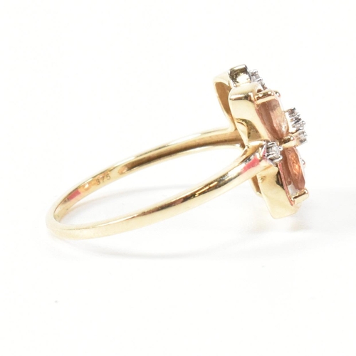 370 - A hallmarked 9ct gold sunstone and diamond cluster ring. The ring having a clover shaped mount set w... 