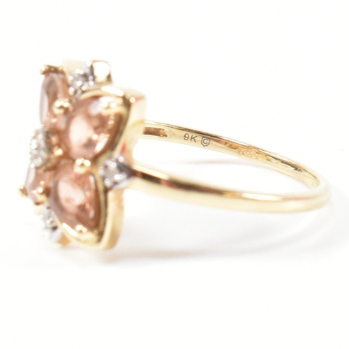 370 - A hallmarked 9ct gold sunstone and diamond cluster ring. The ring having a clover shaped mount set w... 