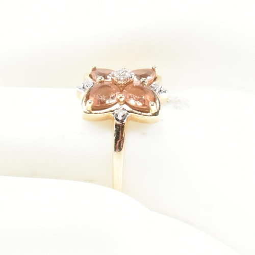 370 - A hallmarked 9ct gold sunstone and diamond cluster ring. The ring having a clover shaped mount set w... 